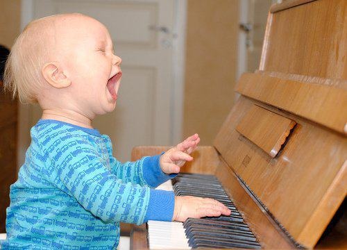 a criança canta ao piano